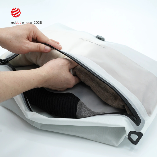 Hands opening a white Compak Large with Divider to show clothing separated on either side of the divider
