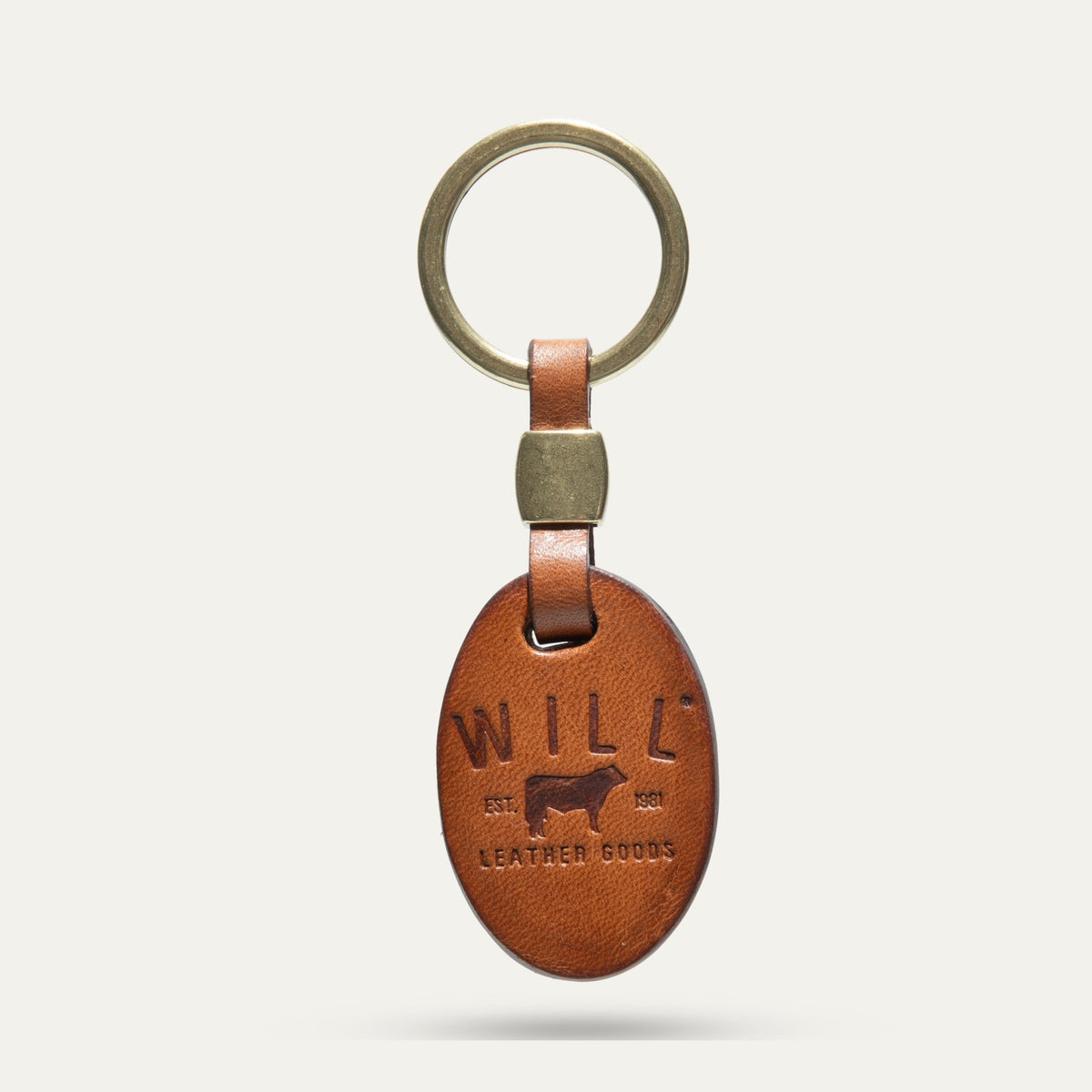 Oval leather key fob in tan, front view, embossed WILL Leather Goods cattle brand logo, brass key ring