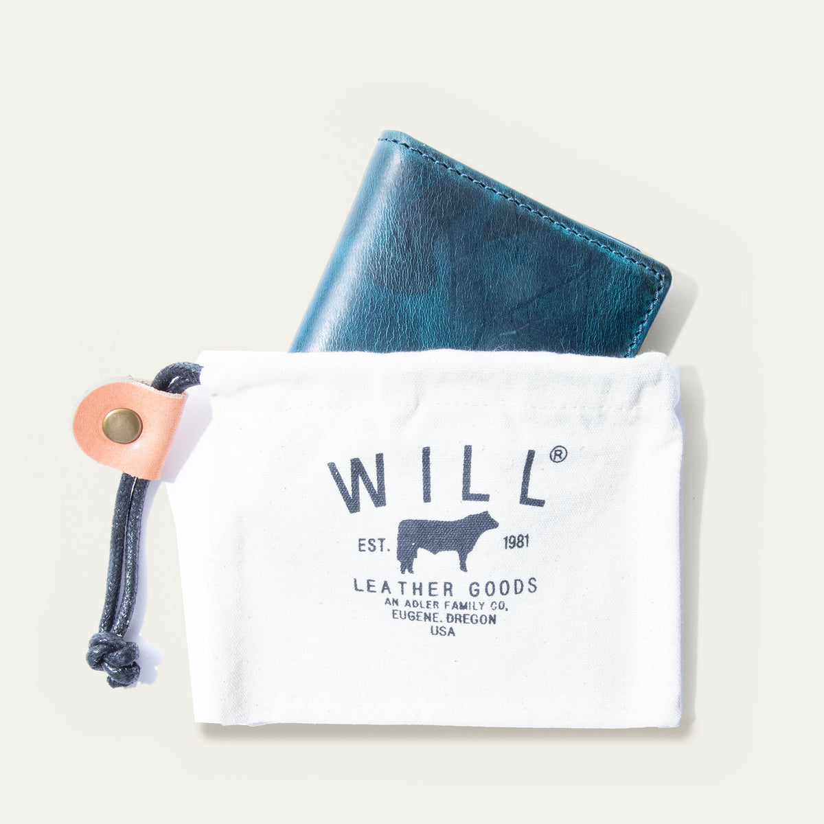 The blue camouflage Military Front Pocket wallet peeking out of a white WILL Leather Goods drawstring pouch.