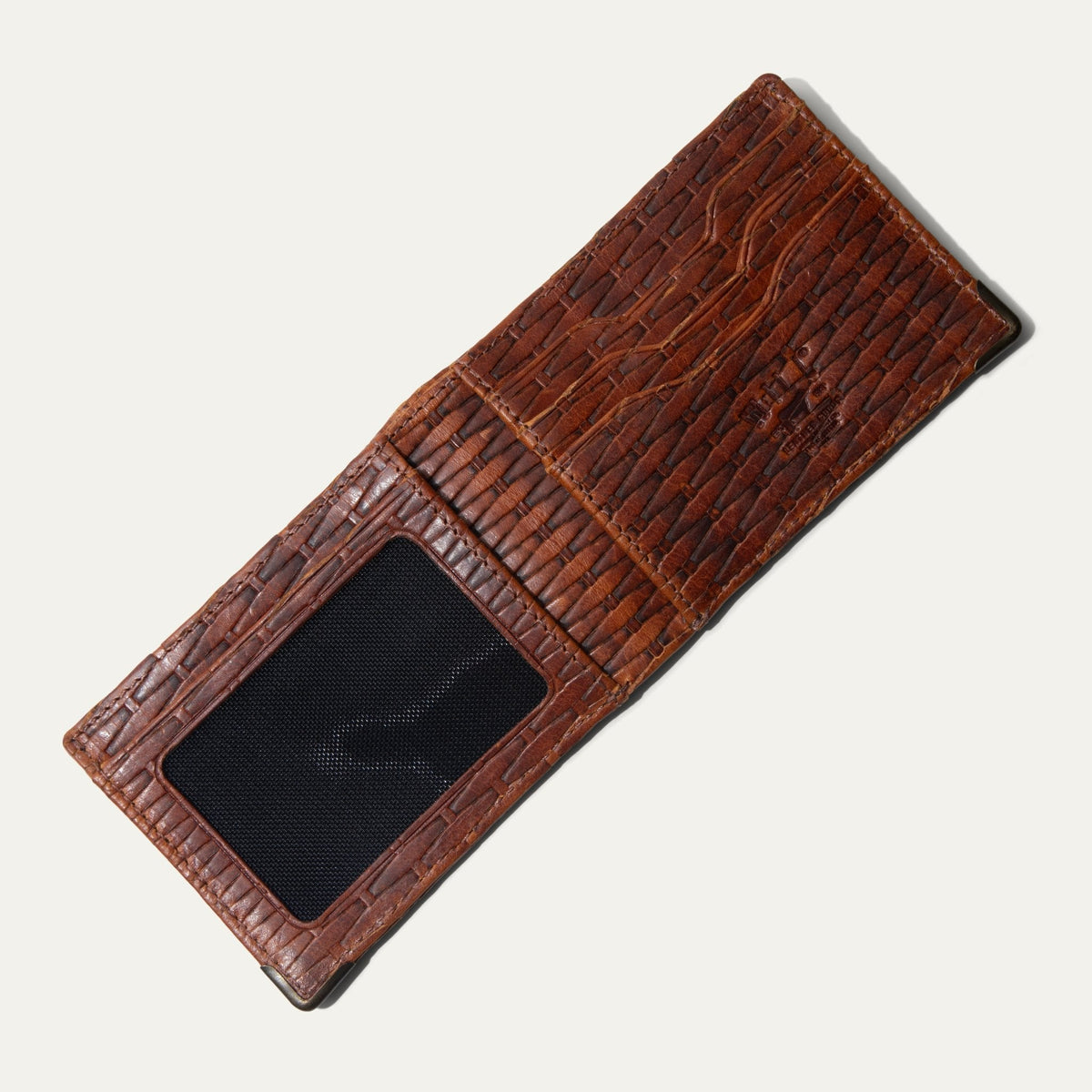 The cognac basketweave Mogul Billfold open with cash and credit cards tucked into the slots, including an American Express and Delta SkyMiles card.