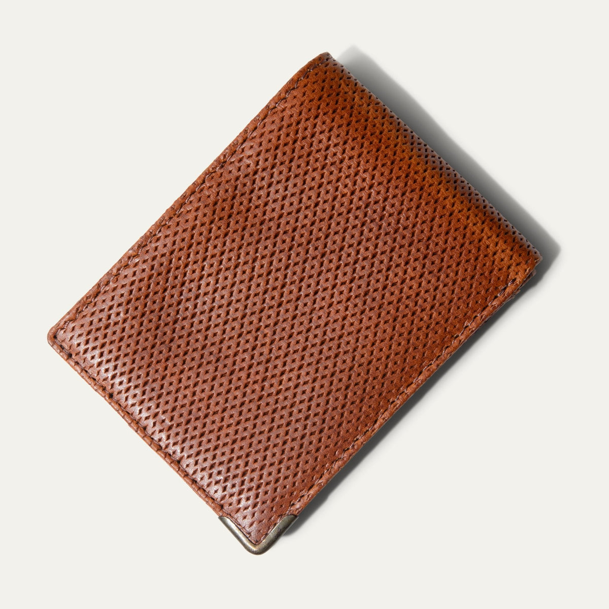 The ginger diamond-perforated Mogul Billfold open with cash and credit cards tucked into the slots, including an American Express and Delta SkyMiles card.