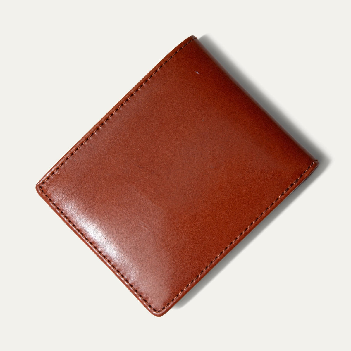 Amber/cognac leather billfold wallet closed, straight-on front view, on a white background.