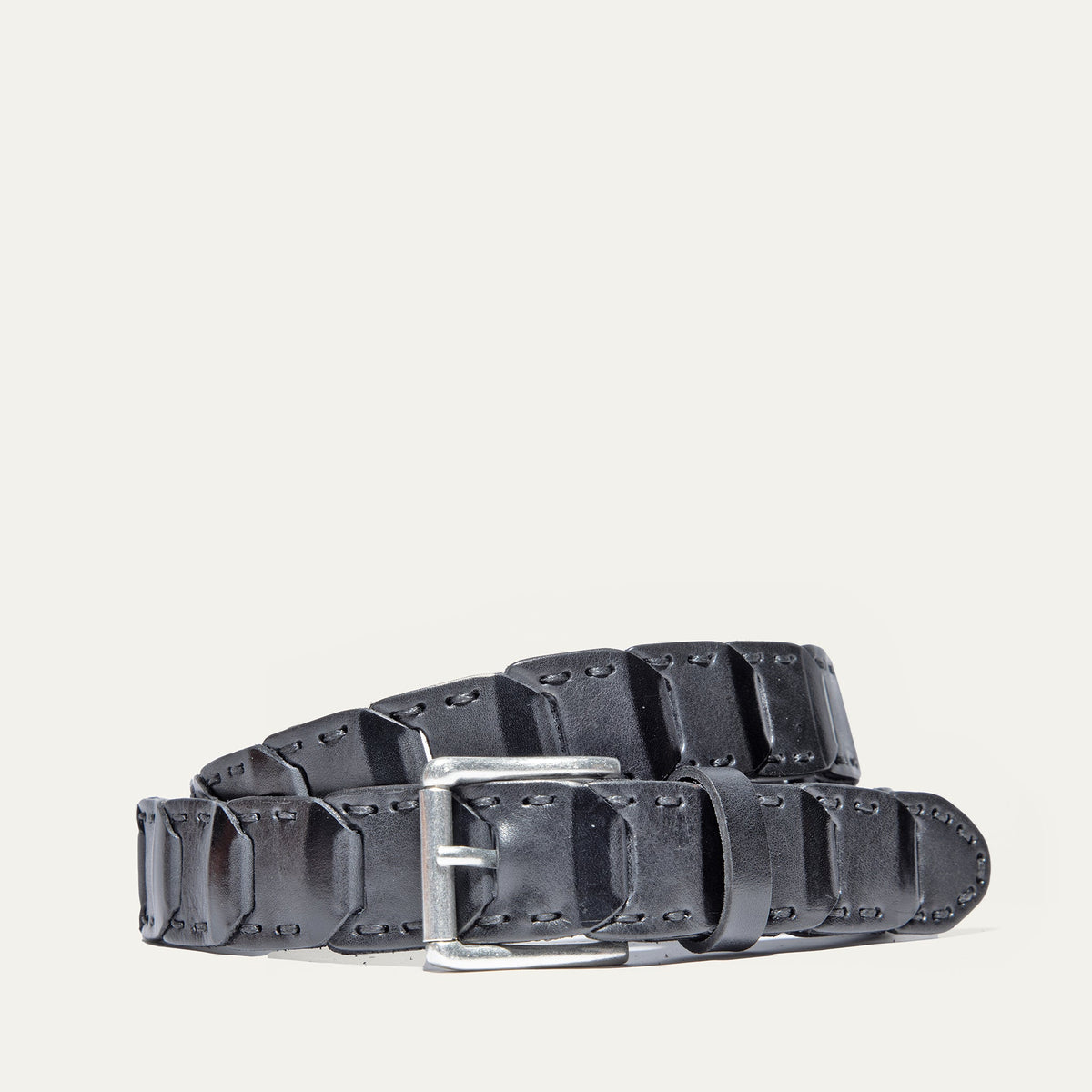 Will Leather Goods Hand Laced Link Belt in black leather, coiled to show the hand-laced rectangular link panels and antique silver roller buckle, on a white background.