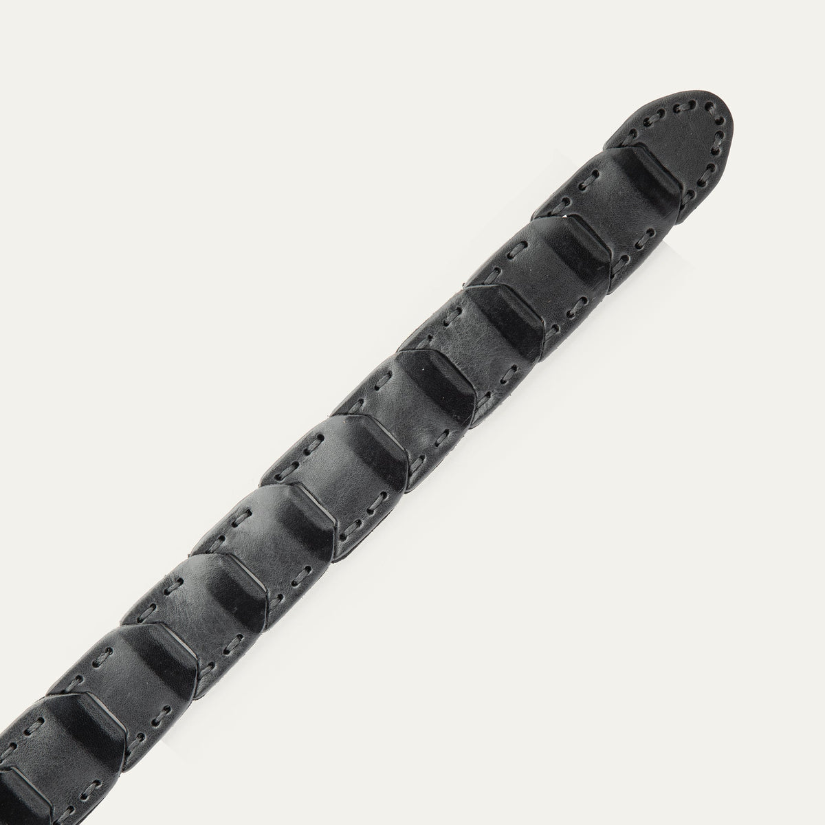 Close-up view of the tapered tip end of the black leather Hand Laced Link Belt, showing the hand-laced rectangular link panels.