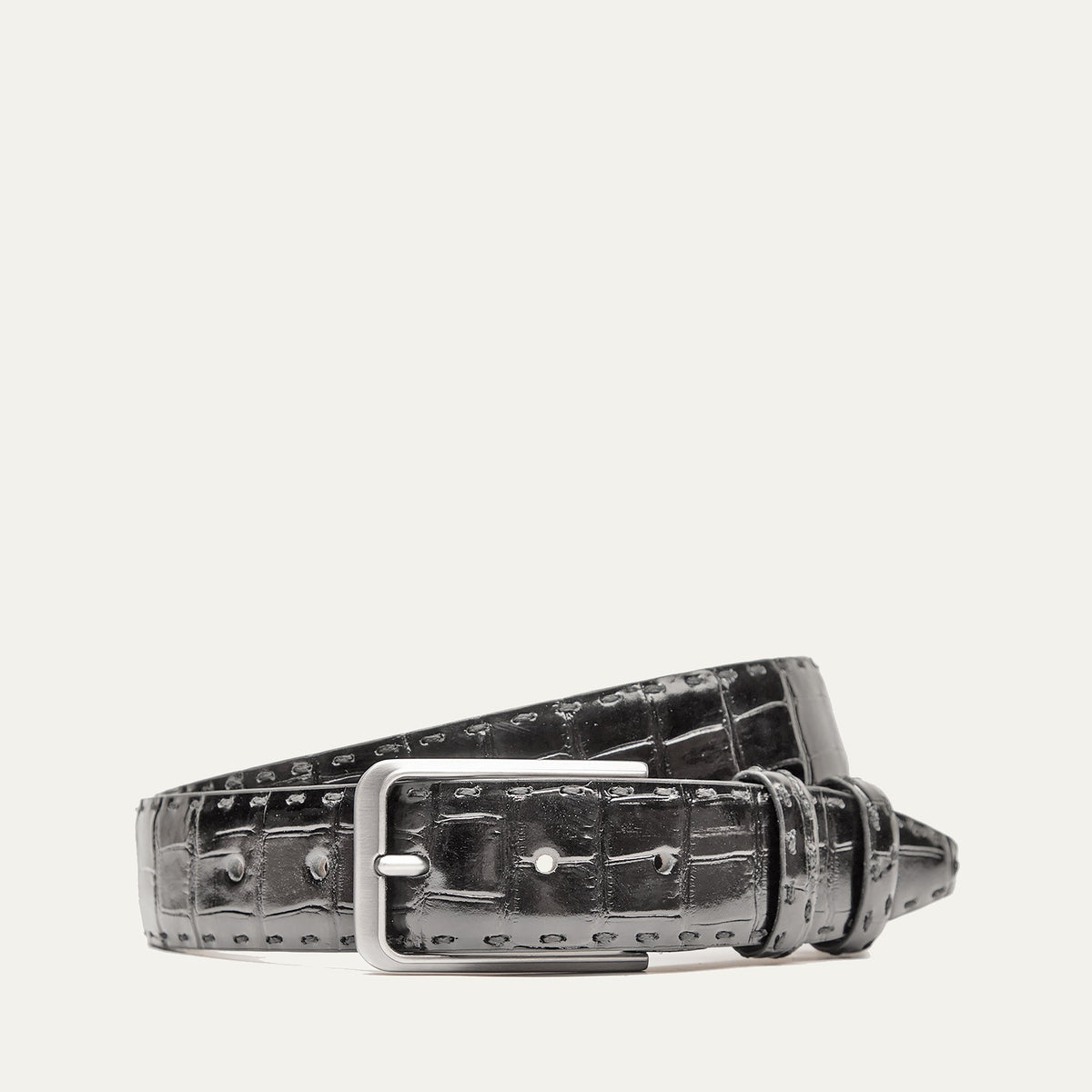 Will Leather Goods Croco Belt in black crocodile-embossed leather with a brushed silver buckle, coiled product shot on a white background.
