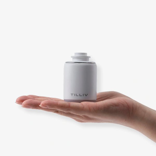 A white TILLIV Nano Pump resting on an open palm, showing how small it is
