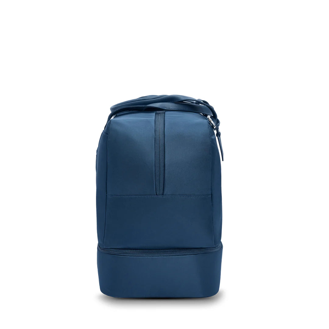 Side view of the Briggs & Riley Rhapsody Weekender Tote in navy blue, showing its slim profile and the bottom zippered expansion compartment