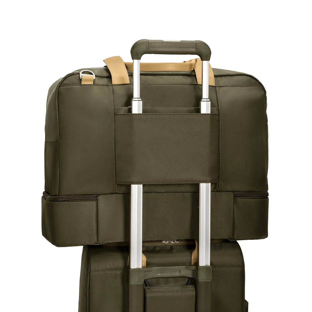 Close-up of the Briggs & Riley Rhapsody Weekender Tote in olive green sliding onto the extended handle of a rolling suitcase via its slip-through back panel