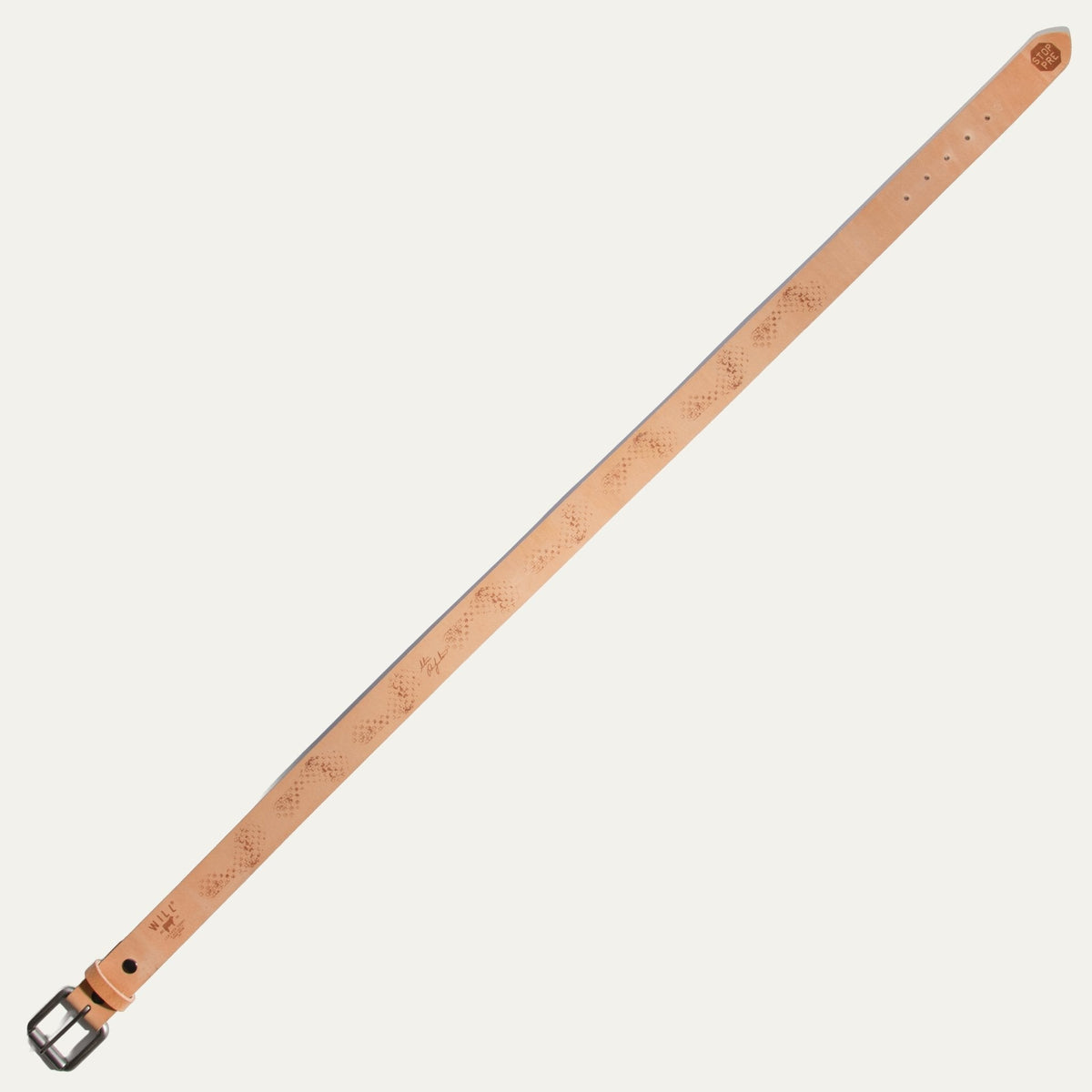 Natural tan leather belt laid out flat diagonally, showing the full length from buckle to tip with the brown waffle-tread emboss pattern and signature stamp