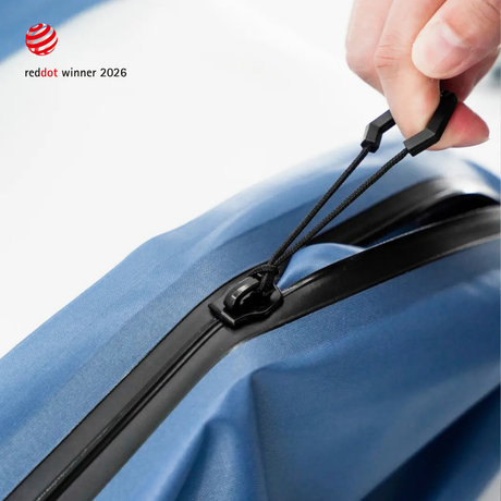 A hand drawing the hexagonal zipper tab along the airtight zipper of a Steel Blue TILLIV Compak pack