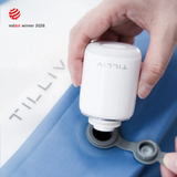 A hand holding a TILLIV Nano Pump against the open one-way valve of a Steel Blue Compak pack, with the valve cap pulled aside