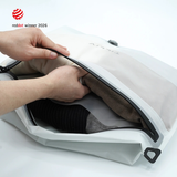 Hands opening a white Compak Large with Divider to show clothing separated on either side of the divider