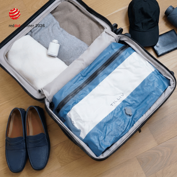Hands opening a Steel Blue Compak Medium with Divider to show clothing separated on either side of the divider