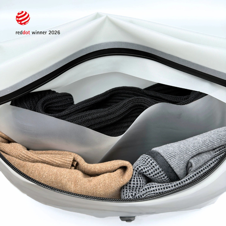 Inside a white Compak Large with Divider: cream and brown knitwear above the grey divider sheet, black and grey garments below it