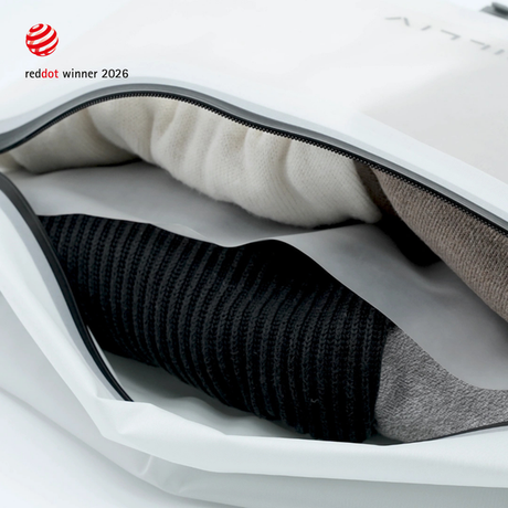 Inside a white Compak Medium with Divider: cream and brown knitwear above the grey divider sheet, black and grey garments below it