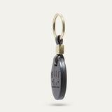 Side profile view of the dark brown leather oval key fob showing its edge and brass keyring hardware
