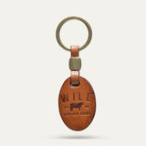 Oval leather key fob in tan, front view, embossed WILL Leather Goods cattle brand logo, brass key ring