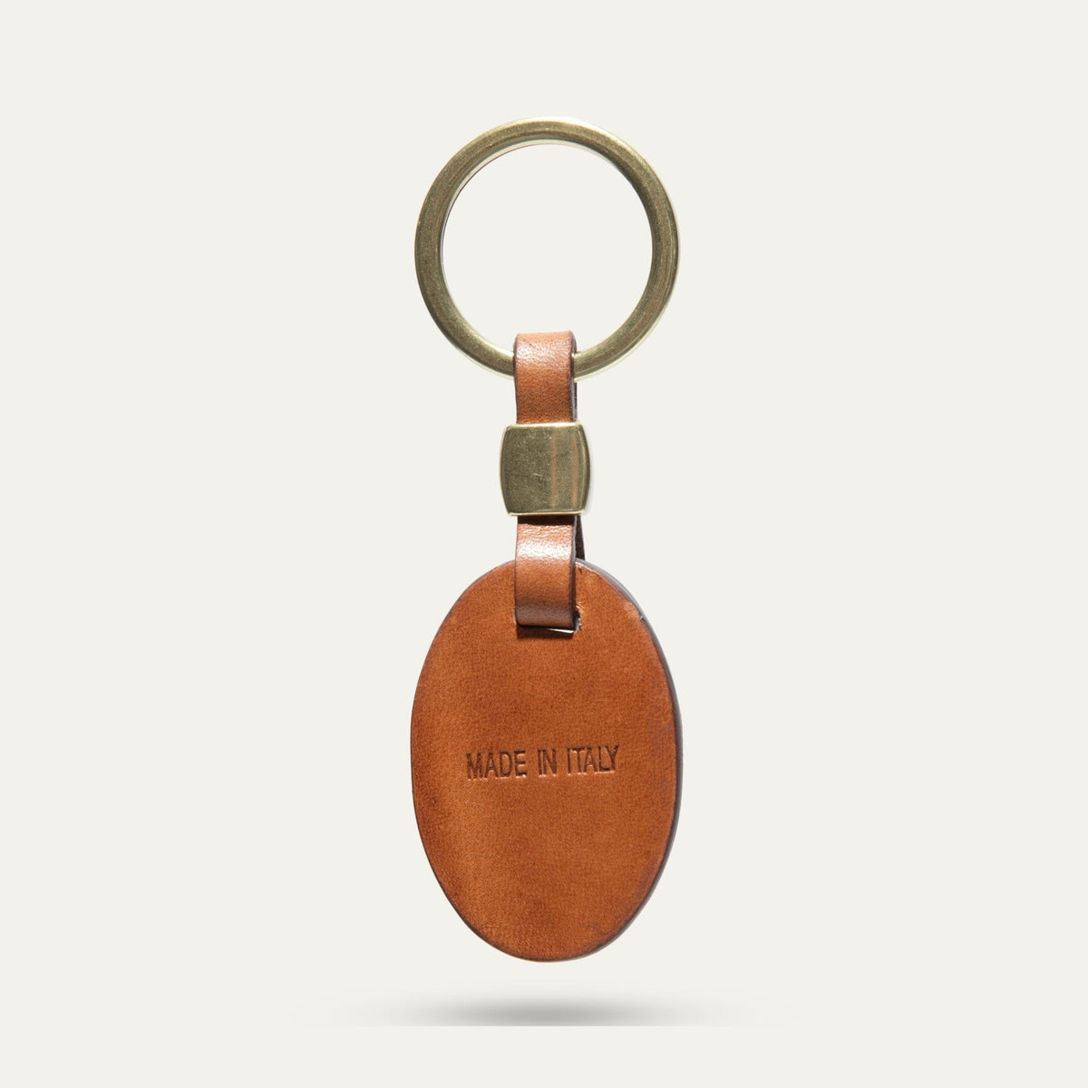 Back view of the tan leather oval key fob with Made in Italy stamp and brass keyring hardware