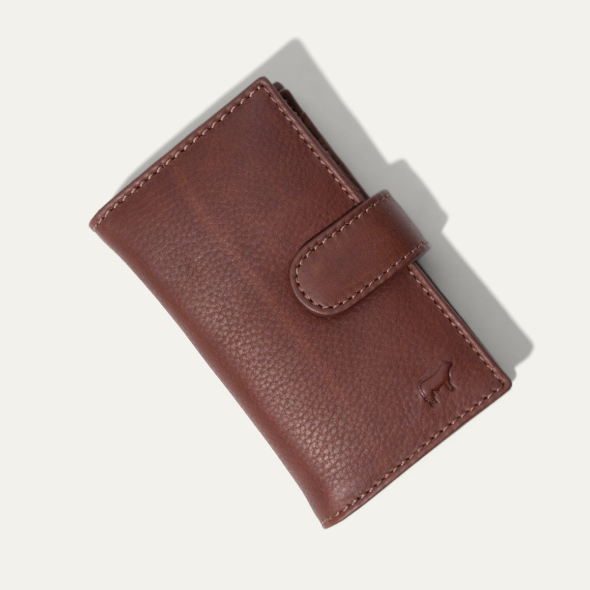 Will Leather Goods Signature Women's Cardholder Wallet in cognac leather, closed with snap tab, embossed cattle-brand logo on the front, on a white background.