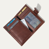 Cognac leather cardholder wallet open, showing card slots, a clear ID window, and a cash pocket holding a bill, on a white background.