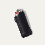 Black leather lighter cover, front view, closed with brass snap and embossed WILL Leather Goods logo