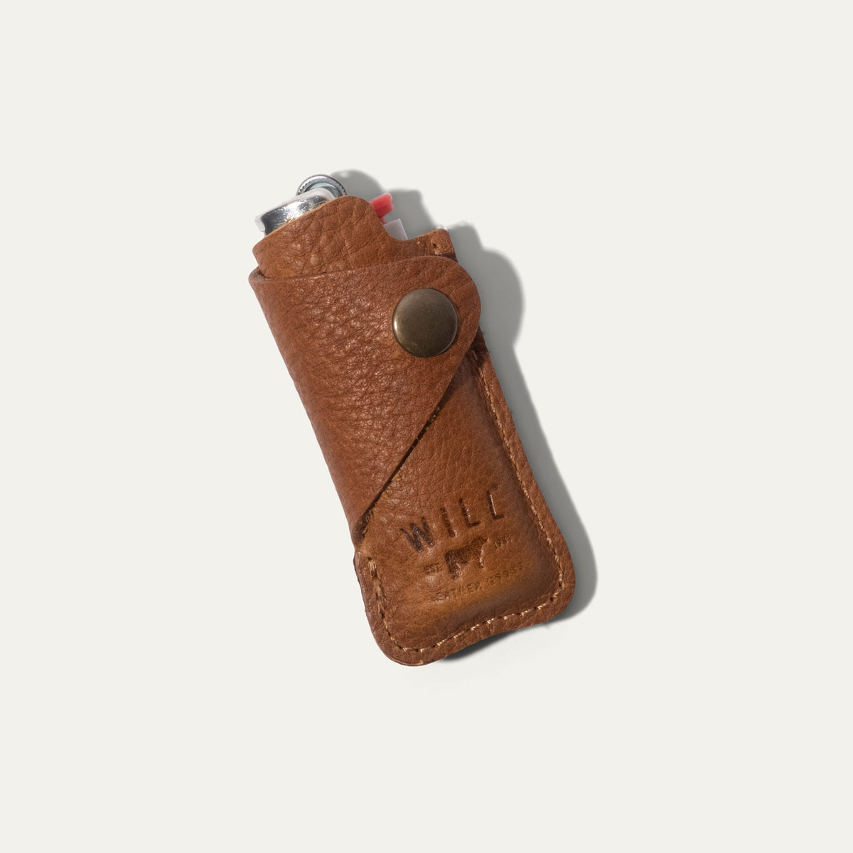 Tan leather lighter cover with a lighter tucked inside, angled view showing the brass snap closure