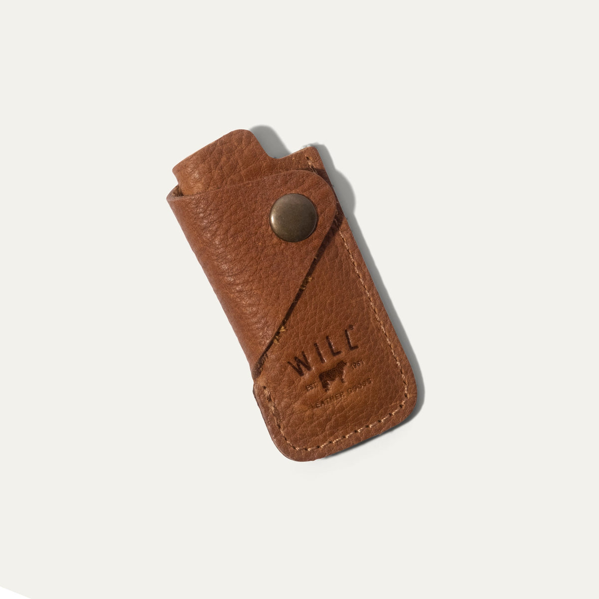 Tan leather lighter cover, front view, closed with brass snap and embossed WILL Leather Goods logo