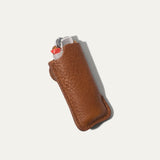 Tan leather lighter cover with lighter visible at top, angled view showing brass snap and embossed WILL Leather Goods logo