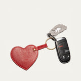 Will Leather Goods Heart Keychain in red leather with embossed WILL logo, attached by a brass ring to a car remote key and a small foot-shaped bottle opener, on a white background.