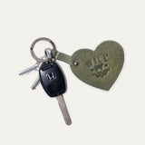 Will Leather Goods Heart Keychain in sage green leather with embossed WILL logo, attached by a brass ring to a Honda car key and two household keys, on a white background.