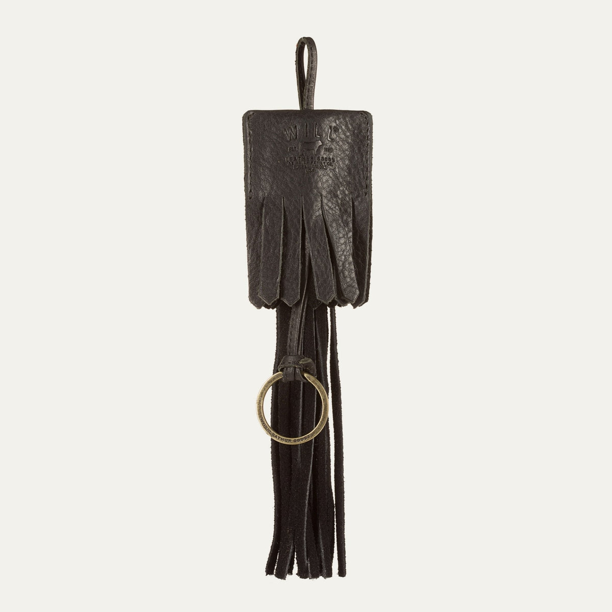 WILL Leather Goods key fob tassel in black leather, straight-on view showing the long fringe strands and embossed leather patch, on a white background.