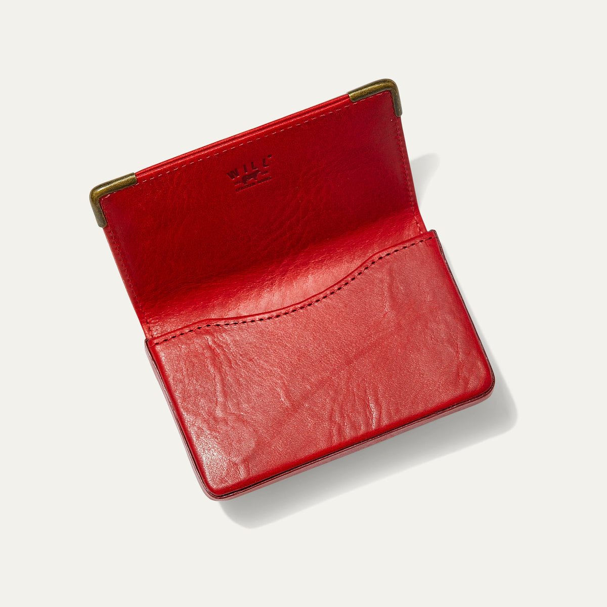 Red leather card holder open flat, showing the empty card pocket