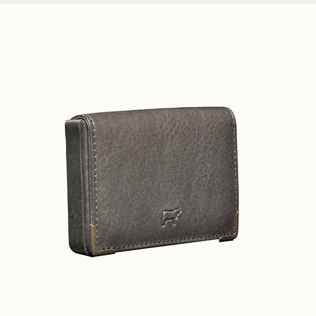 Black leather trifold card holder, three-quarter angle view showing the brass corner guards