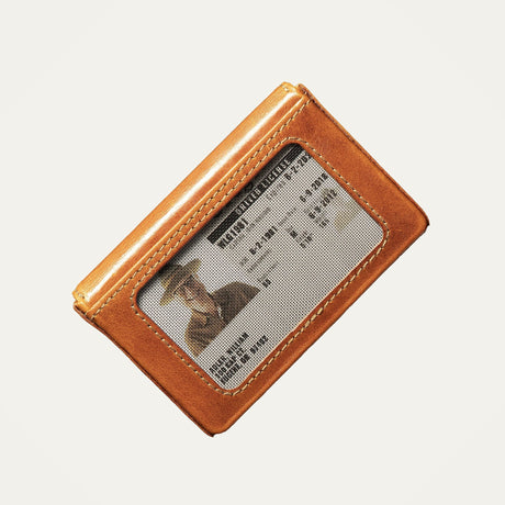Close-up of the cognac leather card holder's clear ID window showing a driver's license