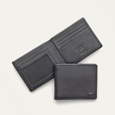 Will Leather Goods Classic Billfold Wallet in black leather, open showing card slots and an ID window, with a closed wallet resting in front showing the embossed cow logo.