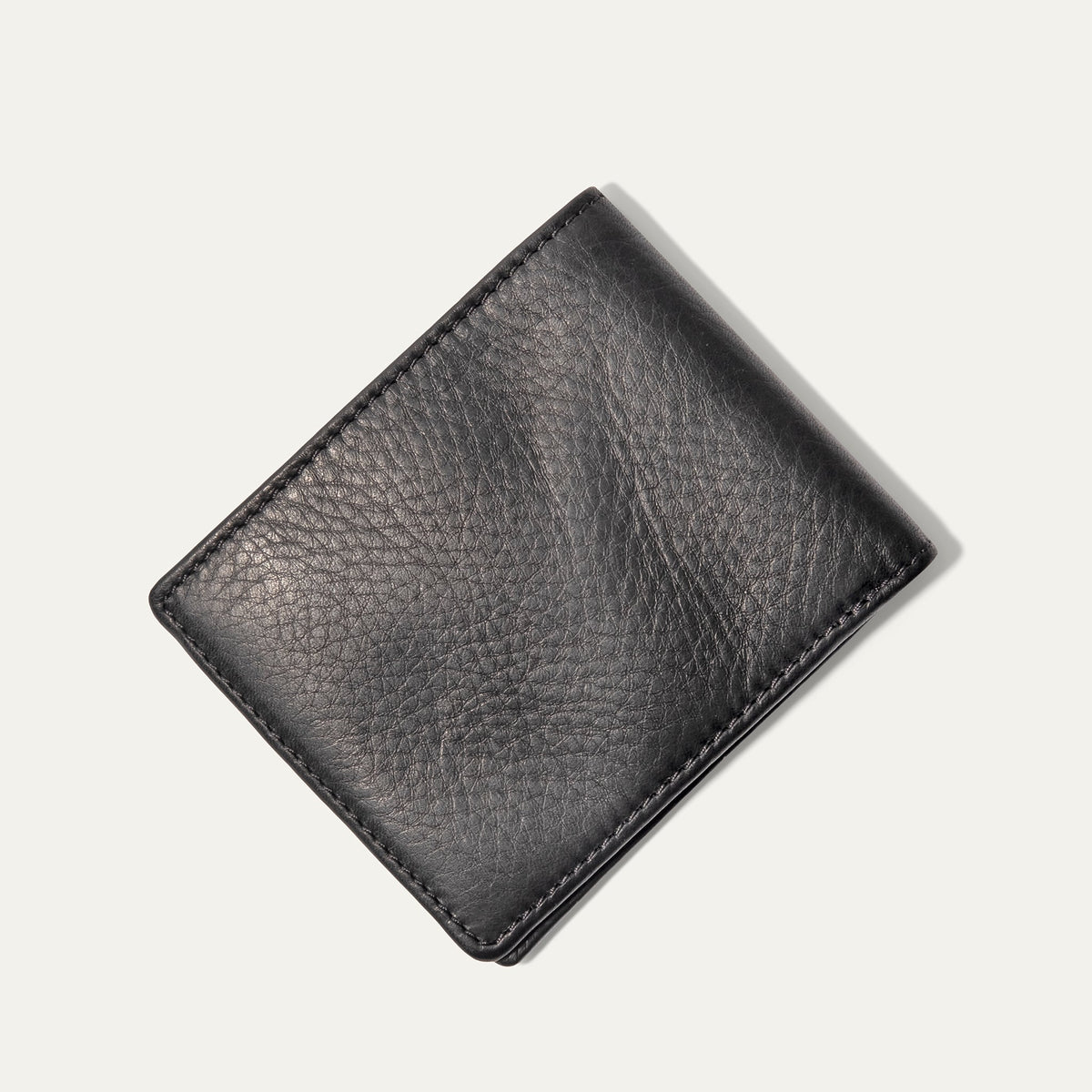 Will Leather Goods Classic Billfold Wallet in black leather, closed, angled view showing the smooth leather texture and embossed cow logo.