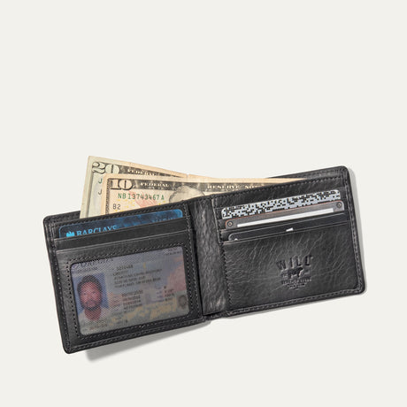 Will Leather Goods Classic Billfold Wallet in black leather, open showing cash, an ID in the window pocket, credit cards, and the embossed WILL Leather Goods logo patch.
