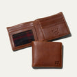 Will Leather Goods Classic Billfold Wallet in tan leather, open showing card slots and a plaid-lined ID window, with a closed wallet resting in front showing the embossed cow logo.