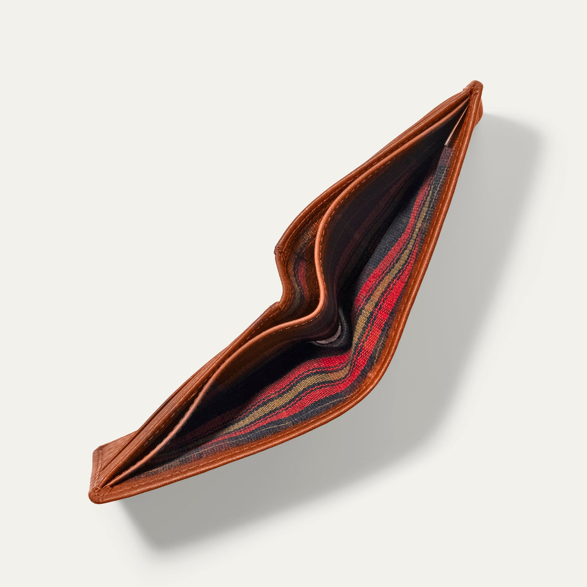 Will Leather Goods Classic Billfold Wallet in tan leather, open and empty, showing the red and black plaid interior lining.