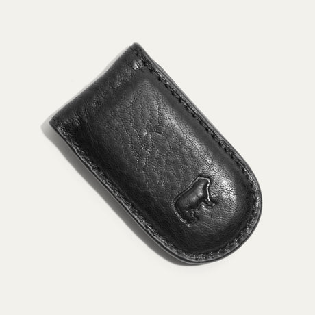 Angled close-up of the black Classic Money Clip holding cash, showing the stitched edge and embossed WILL cattle logo.