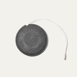 Charcoal gray round leather tape measure case with an embossed cow logo, white cloth measuring tape extended further in an arc showing ruler markings.