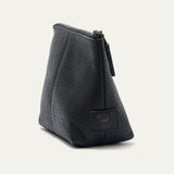 Black pebbled leather zip pouch shown from a three-quarter angle, highlighting the trapezoid shape, zipper pull, and WILL leather patch