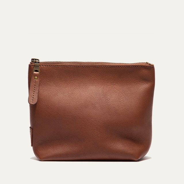 Cognac leather zip pouch shown straight-on, with the zipper pull and WILL leather patch visible on the front
