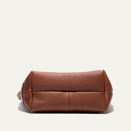 Bottom view of the cognac leather zip pouch, showing the boxed base seams