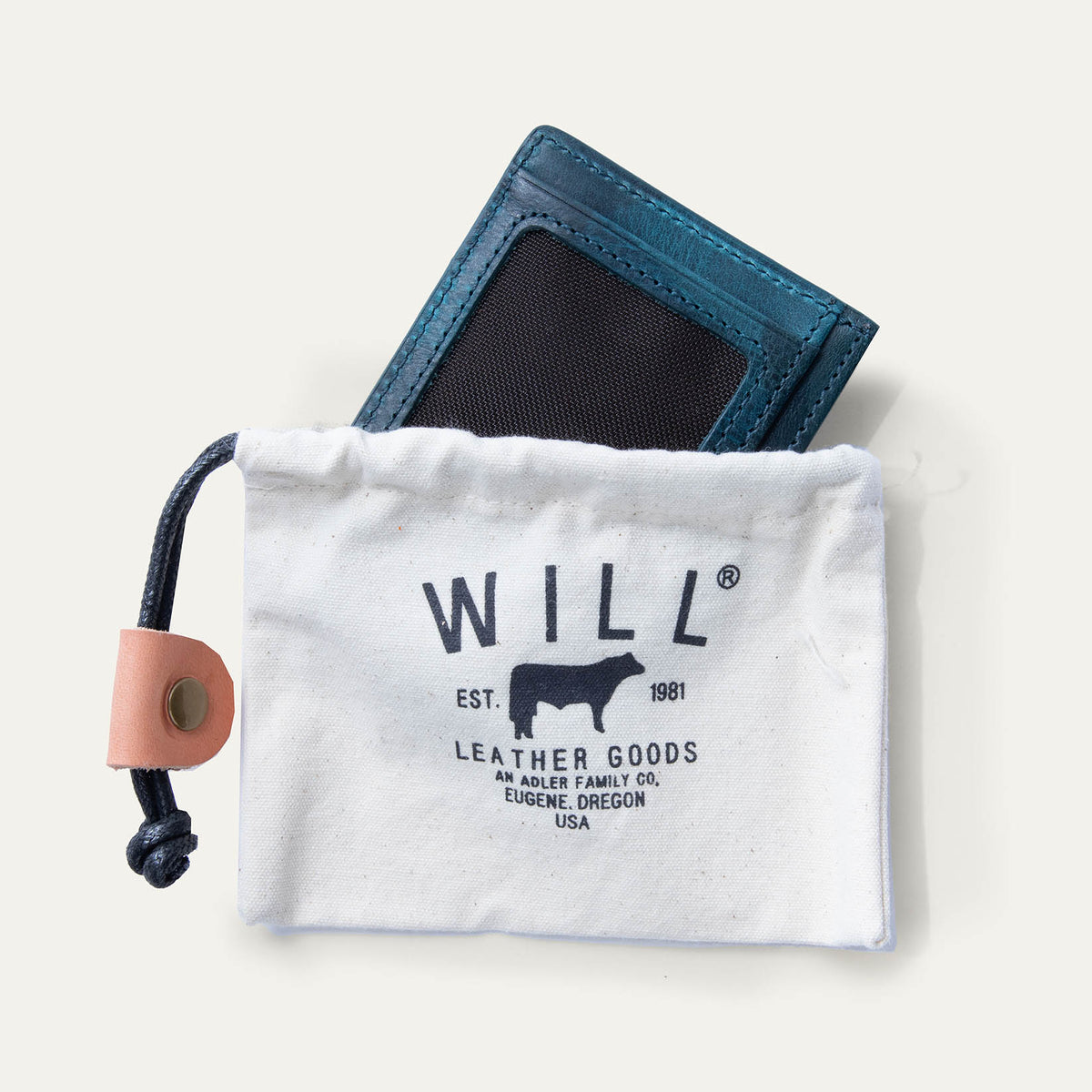 Blue camo leather card case tucked partway into a Will Leather Goods canvas drawstring pouch