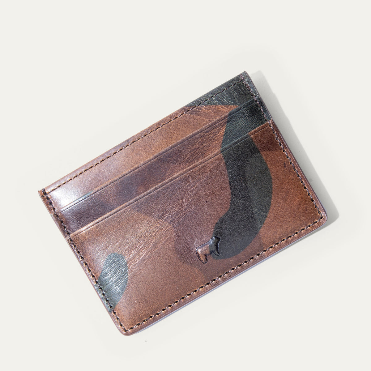 Close-up of the brown camo leather card case's back panel showing card slots and embossed cattle logo