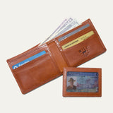 Companion Billfold Wallet by WILL Leather Goods in cognac leather, open with cash fanned out and a Chase Freedom card, American Express, and Delta SkyMiles card visible in the slots.