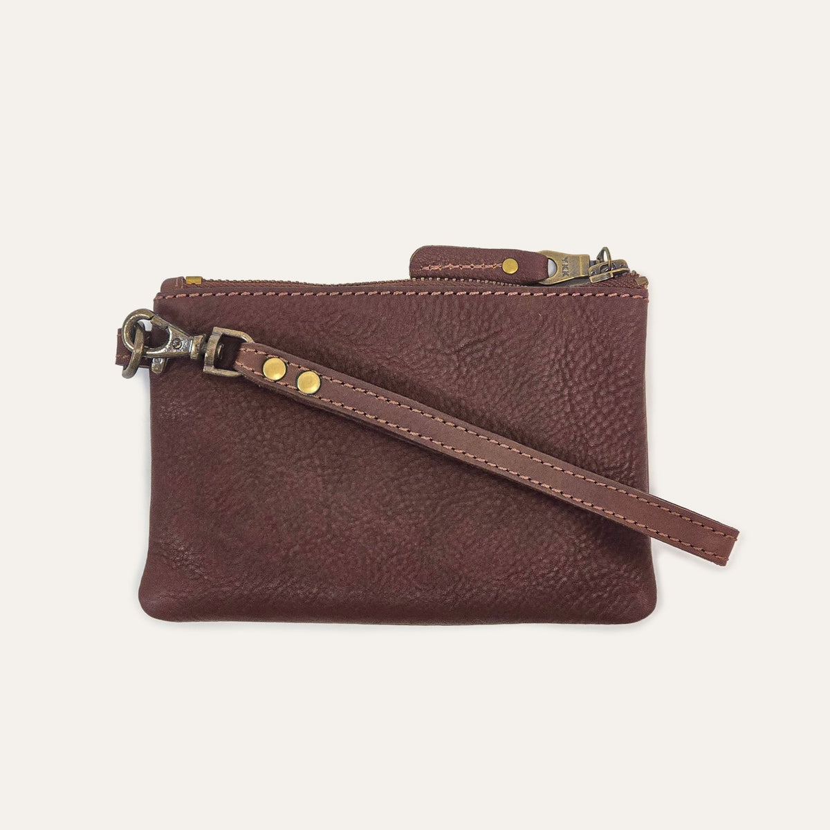 Cognac leather zip pouch, three-quarter view with wristlet strap draped across the front