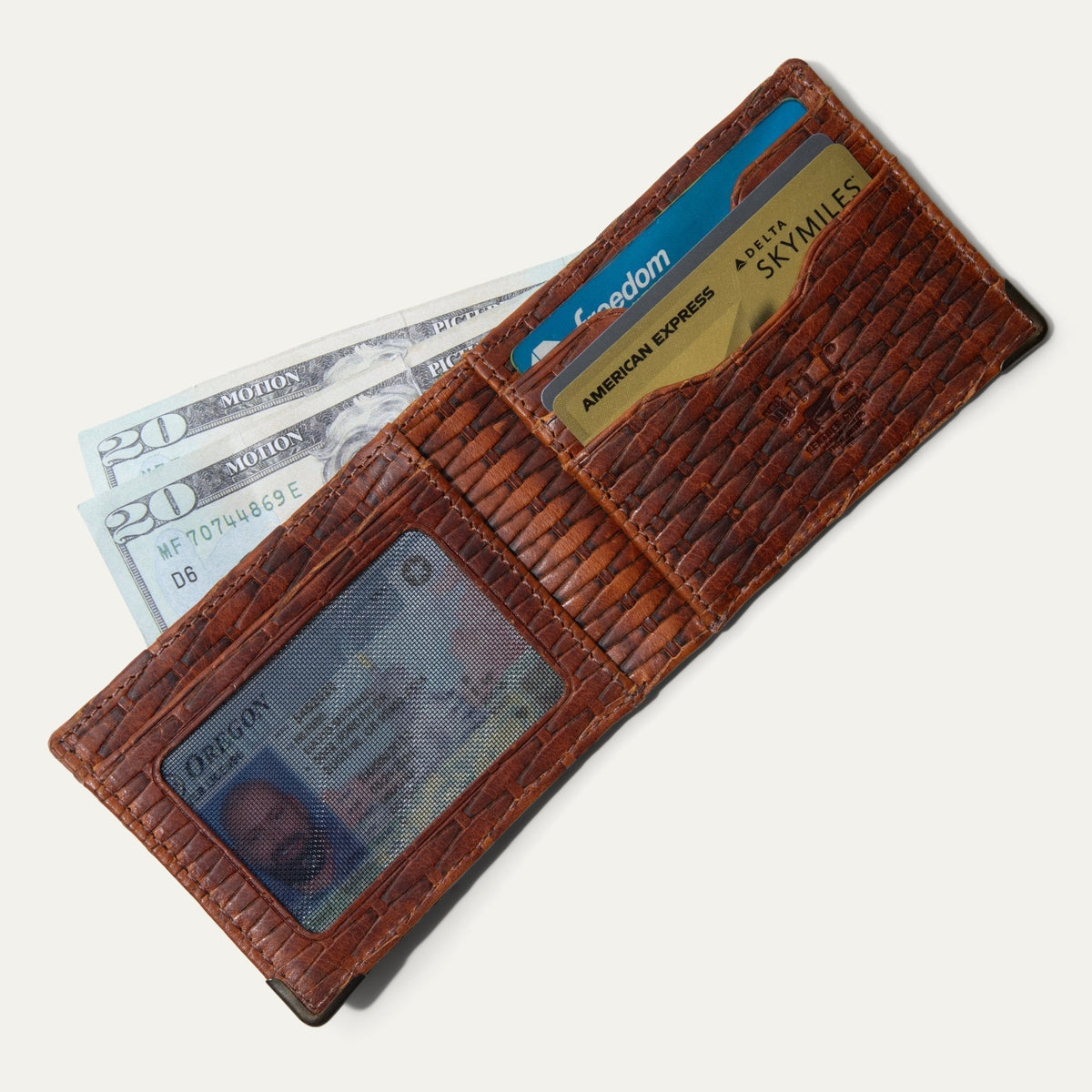 Overhead view of the cognac basketweave Mogul Billfold's card slots and mesh ID window, shown side by side with the folded billfold.