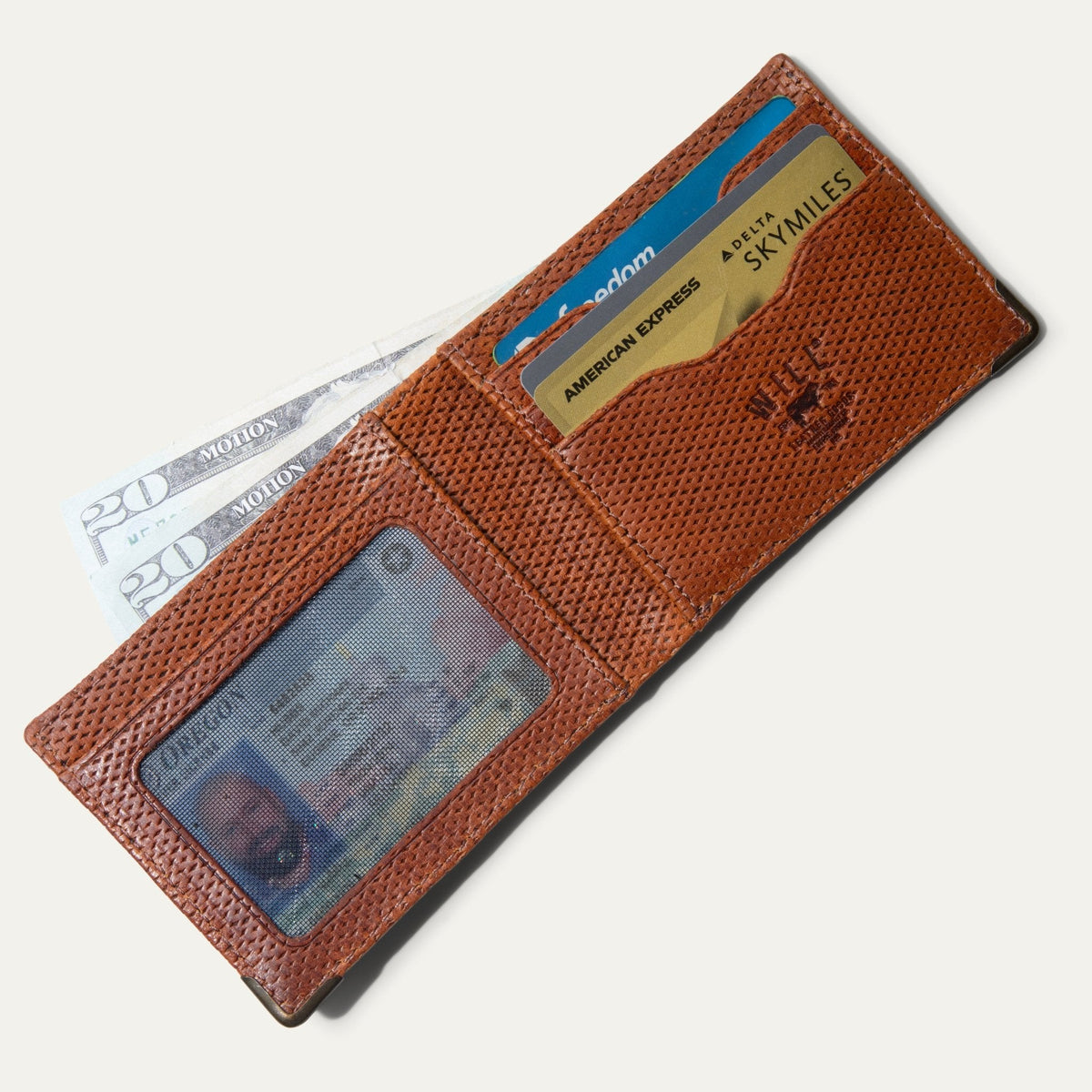 The ginger diamond-perforated Mogul Billfold open with cash, a driver's license in the mesh ID window, and credit cards in the slots.